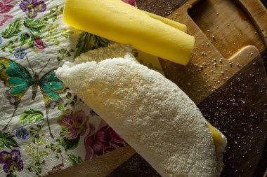 Tapioca, tipik bir Brezilya yemeği, kesme tahtasında mozarella doluyor ve katlanmış renkli bir peçeteye bir dilim mozarella sarılıyor..