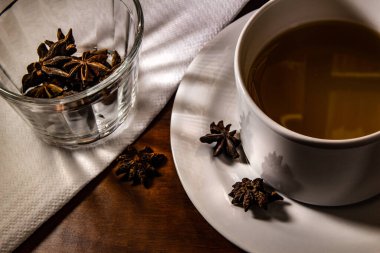 Bir bardak çay ve masaya serpiştirilmiş yıldız anason..