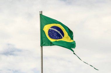 Parçalanmış, yıpranmış Brezilya bayrağı bulutlu bir günde rüzgarda dalgalanıyor..