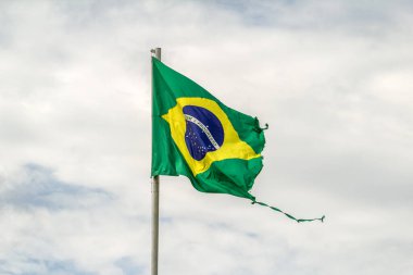 Parçalanmış, yıpranmış Brezilya bayrağı bulutlu bir günde rüzgarda dalgalanıyor..