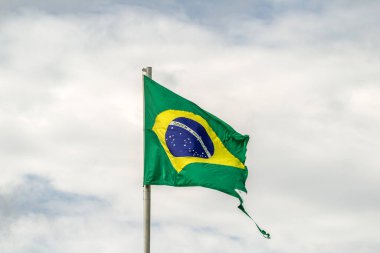 Parçalanmış, yıpranmış Brezilya bayrağı bulutlu bir günde rüzgarda dalgalanıyor..