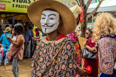 Goiania şehrinde düzenlenen geleneksel Brezilya dini festivalinde maske ve şapka takan bir eğlence düşkünü..