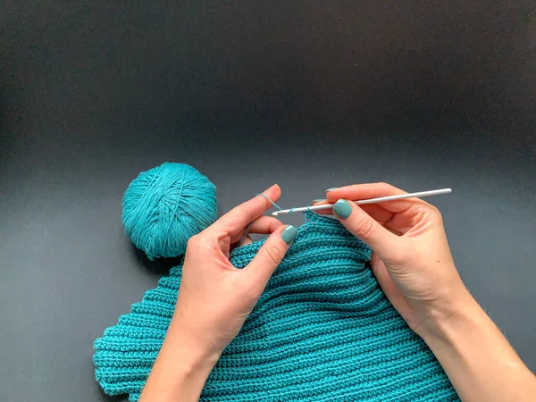 黒の背景にクロッキー ターコイズの糸のプロセス 糸の皮とかぎ針編みのフック 自分の手で製品を作るというコンセプト 針仕事趣味趣味 — ストック写真
