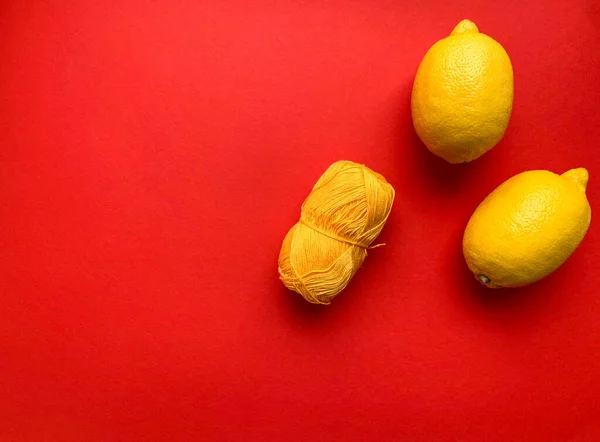 Due Limoni Gialli Una Matassa Gialla Filato Fondo Rosso Limone — Foto Stock