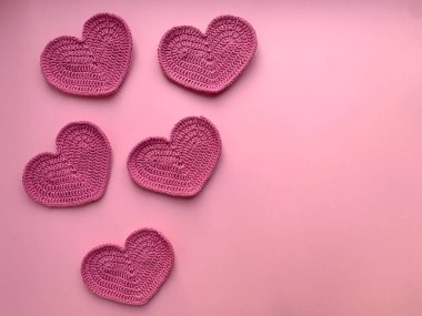 Pembe arka planda pembe kalpler ördüm. Fotoğraf yukarıdan. Ürün yaratma kavramı. Tığ işi. Sevgililer Günü 