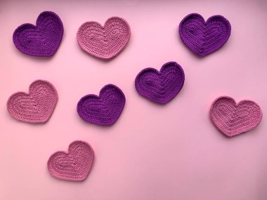 Pembe renkli kalpler ve pembe arka planda leylak renkleri. Fotoğraf yukarıdan. Ürün yaratma kavramı. Tığ işi. Sevgililer Günü konsepti