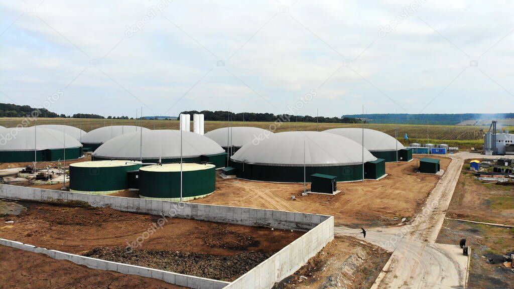 Biogas. Aerial view of a biogas plant and a farm in green fields. Renewable energy from biomass. Modern agriculture in Ukraine and the European Union.