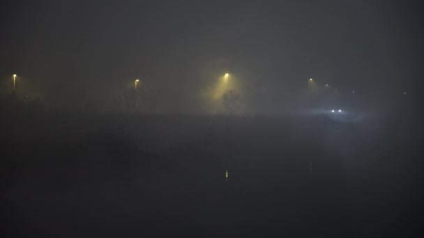 Vehículo solitario conduciendo en una espesa niebla nocturna cerca del pantano islandés — Vídeo de stock