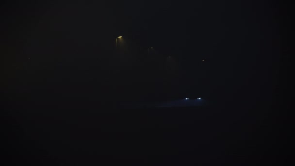 Faróis de carro e lâmpadas de steet brilhando através de nevoeiro preto pitch — Vídeo de Stock