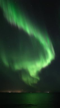 Parlak aurora borealis okyanusa yansıyor, dikey görünüm oranı