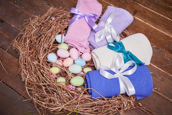 复活节彩蛋与设置的柳条窝干草钩织的毯子覆盖着丝绸缎带复活节圣洁庆祝，快乐，本 免版税图库照片