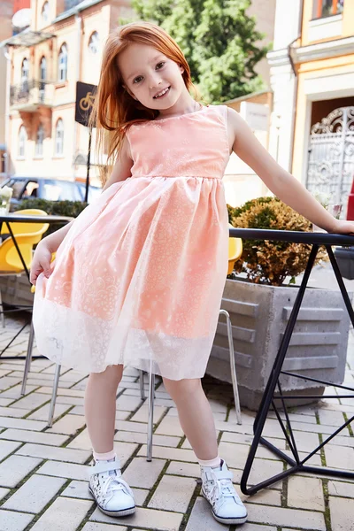 Small baby girl pretty kid happy childhood wear fashion dress sneakers walk run on the street cafe restaurant bright hair color cute smile building chair summer dance daughter — Stock Photo, Image