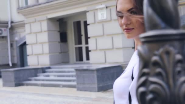 Femme marchant sur la rue romantique date yang dame longue brune cheveux ondulés vent chaud été bâtiments météorologiques robe noire et blanche style de mode — Video