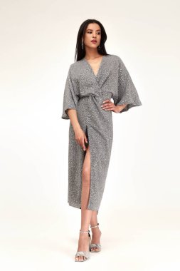 Moda mankeni, çekici yaşam tarzı seksi esmer kadın. Giysileri midi gümüş rengi. Parlak topuklu ayakkabılar..