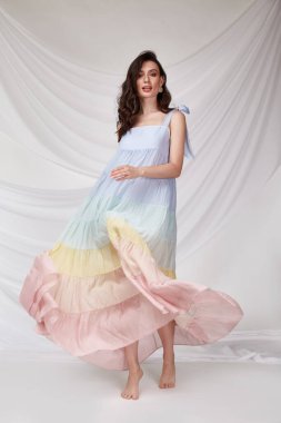 Güzel, seksi bir kadın açık renkli ipek elbise giyer yaz koleksiyon partisi günlük tarz esmer saçlar güzel yüz makyajı beyaz arka plan stüdyosu.