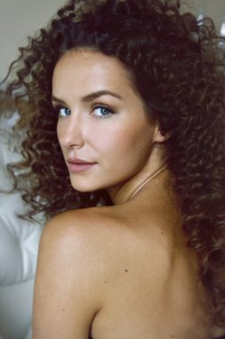 bared omuz arka oturma ile mavi gözlü kıvırcık kız portresi