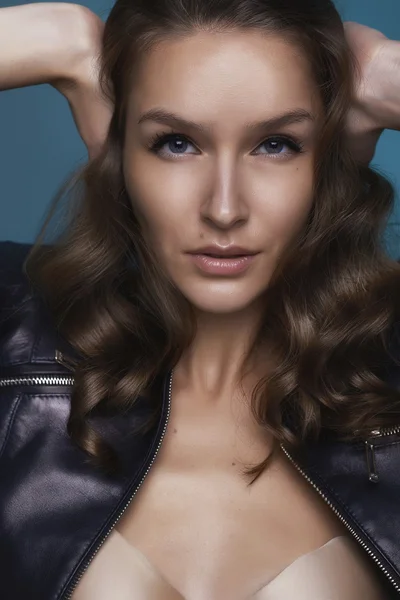 Portrait of the  beautiful girl with shining tanned skin and Big Blue Bright eyes and curly hair on a blue background and cover her ears cause don't want to listen — Stock Photo, Image