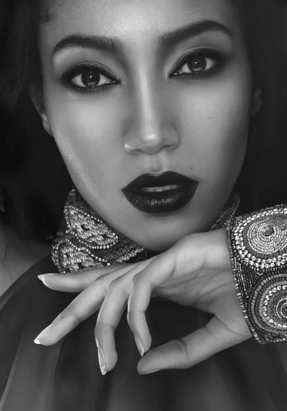 Retrato de moda en blanco y negro de la hermosa mulata con piel oscura, cabello y labios rojos en accesorios étnicos tradicionales, y pulsera en su mano — Foto de Stock