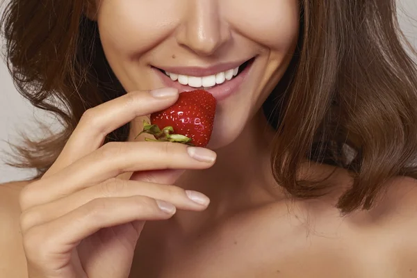 Bella ragazza con sorriso perfetto mangiare fragola rossa. denti bianchi e cibo sano — Foto Stock