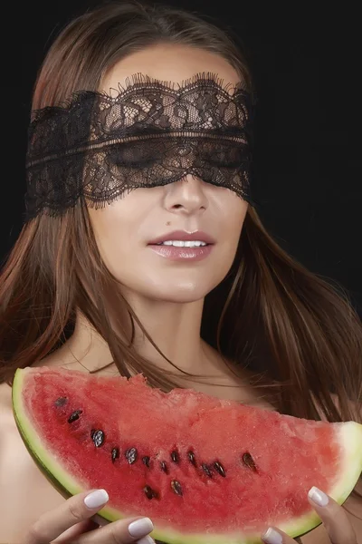 Young beautiful sexy woman with dark lace on eyes bare shoulders and neck, holding watermelon to enjoy the taste and are dieting, feeling temptation, teeth passion sexy lips — Stock Photo, Image