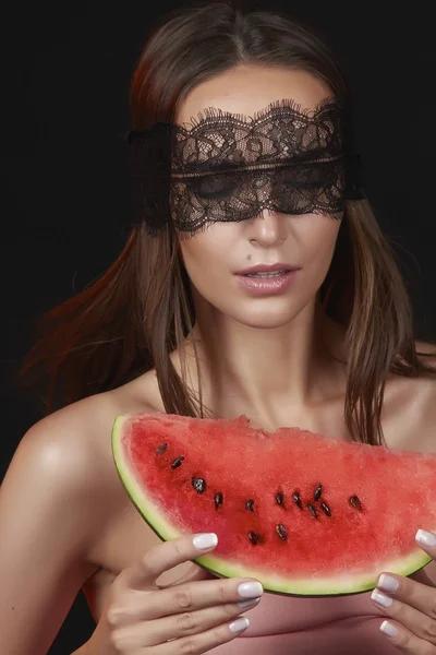 Young beautiful sexy woman with dark lace on eyes bare shoulders and neck, holding watermelon to enjoy the taste and are dieting, feeling temptation, teeth passion sexy lips — Stock Photo, Image