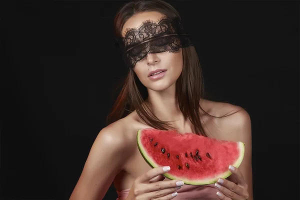 Young beautiful sexy woman with dark lace on eyes bare shoulders and neck, holding watermelon to enjoy the taste and are dieting, feeling temptation, teeth passion sexy lips — Stock Photo, Image