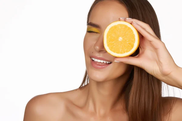 Mooie sexy jonge vrouw met perfecte gezonde huid en lang bruin haar dag make-up blote schouders houden oranje citroen grapefruit gezonde eten van biologisch voedsel dieet weight loss — Stockfoto