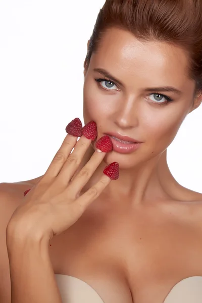 Beautiful sexy brunette woman holding four berries on her fingers, sexy smiling and is going to eat raspberries on a white background, healthy food, tasty food, organic — Stock Photo, Image