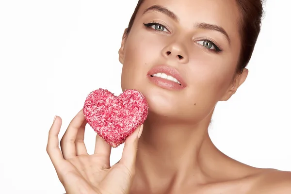 Beautiful sexy brunette woman eating cake shape of heart on a white background, healthy food, tasty, organic, romantic valentine day — Stock Photo, Image