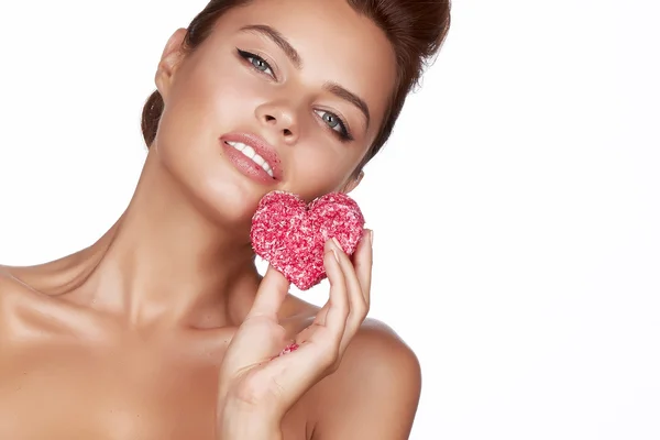 Beautiful sexy brunette woman eating cake shape of heart on a white background, healthy food, tasty, organic, romantic valentine day — Stock Photo, Image