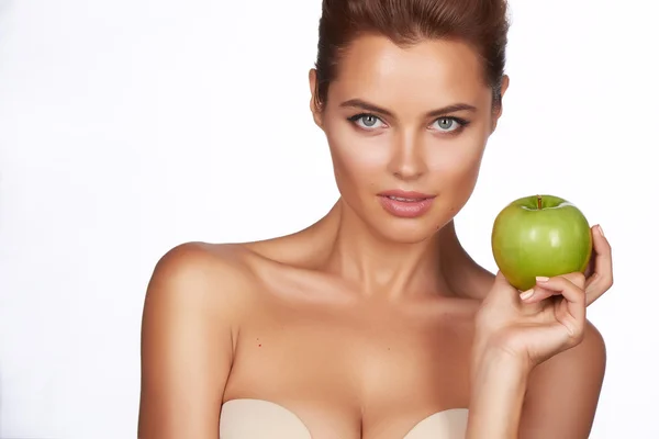 Young beautiful sexy girl with dark curly hair, bare shoulders and neck, holding big green apple to enjoy the taste and are dieting, healthy eating and organic foods, feeling temptation, smile, teeth — Stock Photo, Image