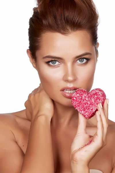 Beautiful sexy brunette woman eating cake shape of heart on a white background, healthy food, tasty, organic, romantic valentine day — Stock Photo, Image