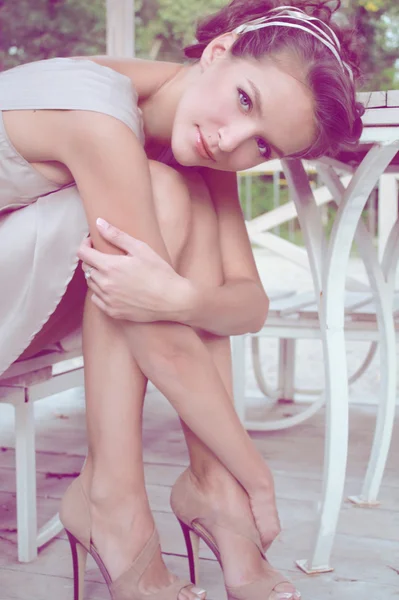 Vrouw zitten in een gazebo dragen een beige zijden jurk — Stockfoto