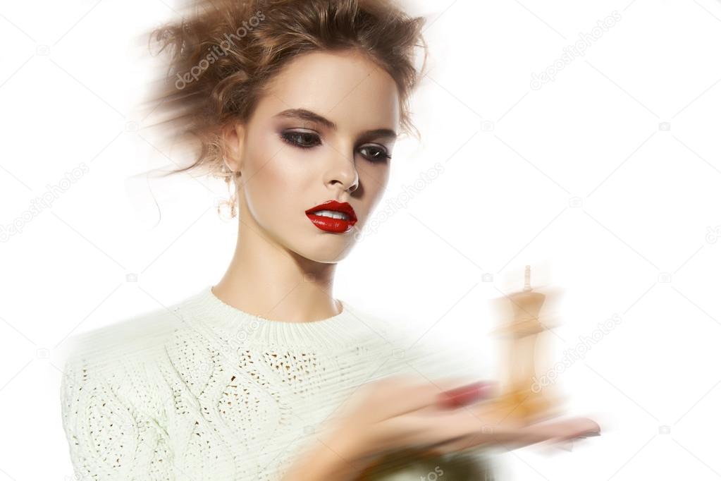 Beautiful woman with evening make-up holding a king chess piece