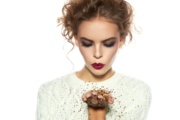 Beautiful girl with evening makeup blow gold sequins — Stock Photo, Image