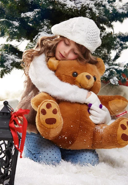 Hermosa niña sentada en la nieve en los árboles de Navidad — Foto de Stock