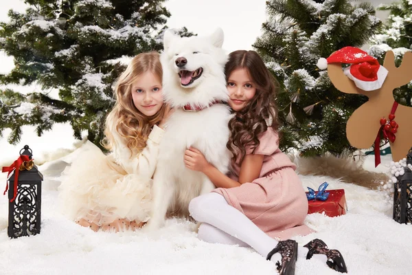 Hermosa niña sentada en la nieve en los árboles de Navidad — Foto de Stock