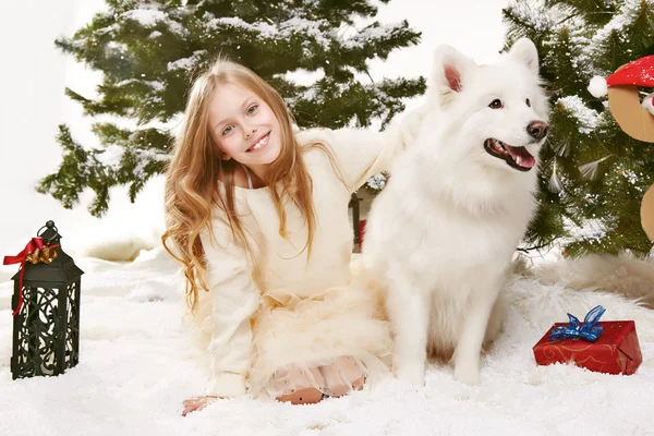 Beautiful little girl sitting in the snow at Christmas trees — Stock Photo, Image