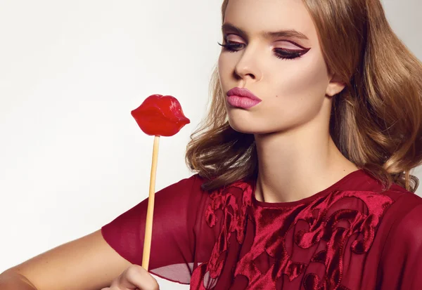 Beautiful sexy woman in silk dress with candy lips on stick — Stock Photo, Image