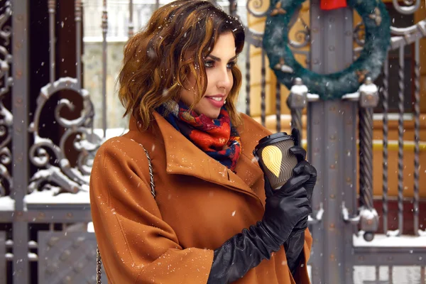 Woman with cup of coffee walk on snow street Christmas New Year — Stock Photo, Image