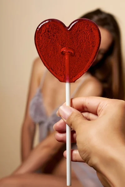 Mooie vrouw lachende covers één oog lollipop rood horen — Stockfoto