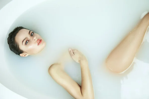 Красивая сексуальная женщина в ванной с молочным спа косметическим телом Стоковое Фото