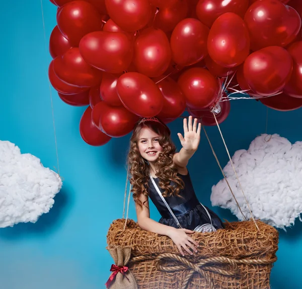 Pequena menina bonito voando em balões de coração vermelho dia dos namorados — Fotografia de Stock