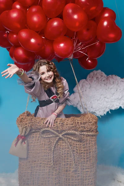 Pequena menina bonito voando em balões de coração vermelho dia dos namorados — Fotografia de Stock
