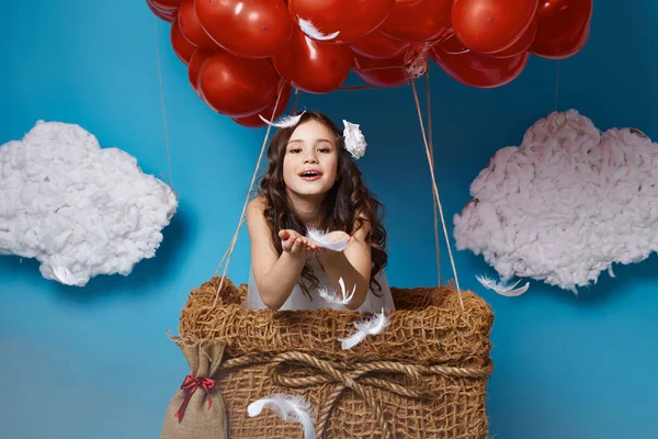 Pequena menina bonito voando em balões de coração vermelho dia dos namorados — Fotografia de Stock