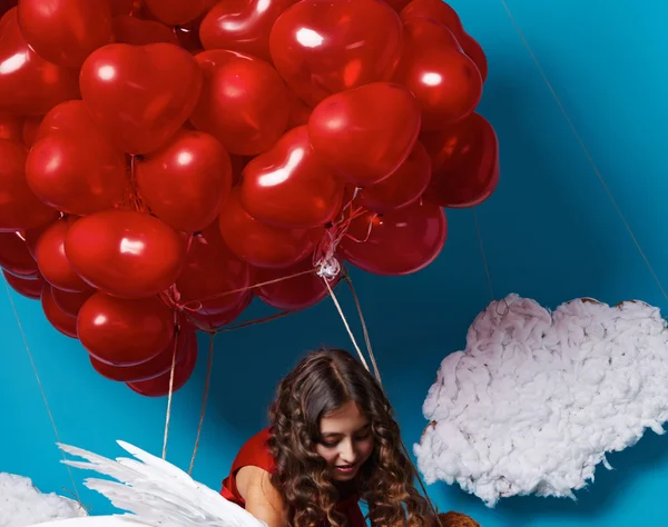 Pequena menina bonito voando em balões de coração vermelho dia dos namorados — Fotografia de Stock