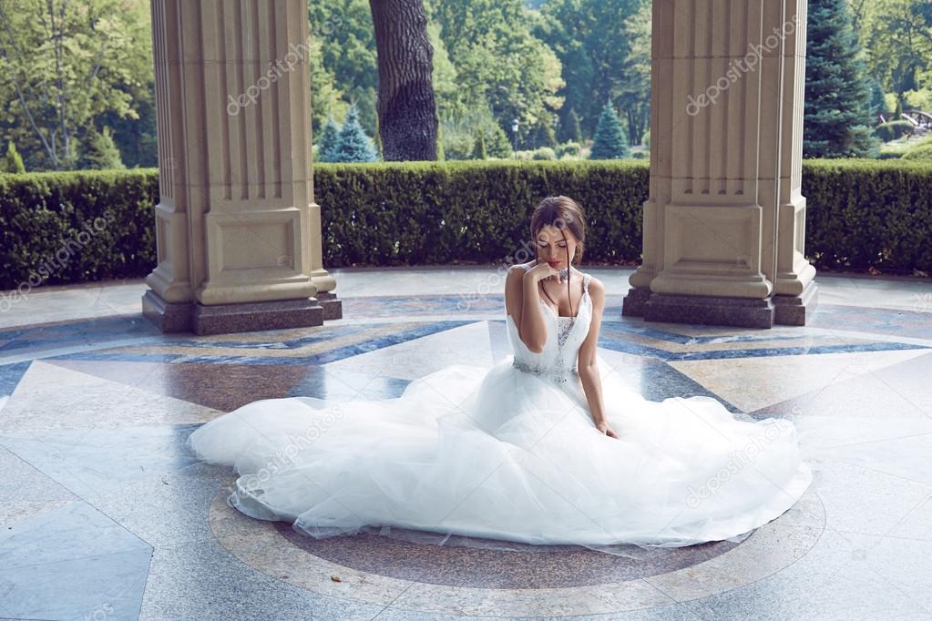 Beautiful young woman sexy brunette bride in a luxury white wedding dress the nature Castle Summer happiness awaits the groom before the wedding ceremony