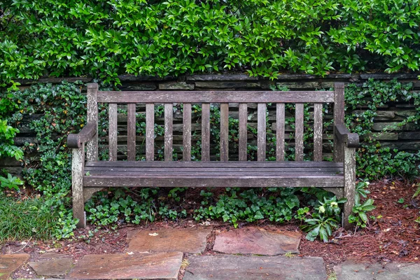 Banc de parc en bois vieilli sur pierre de drapeau — Photo