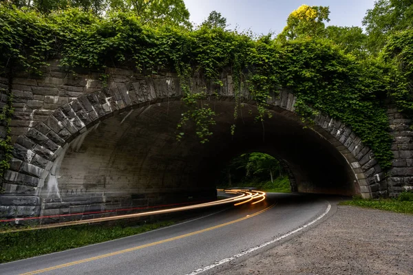 Reflektory Samochodu Przejeżdżającego Przez Kamienny Tunel Pokryty Bluszczem Parku Narodowym — Zdjęcie stockowe
