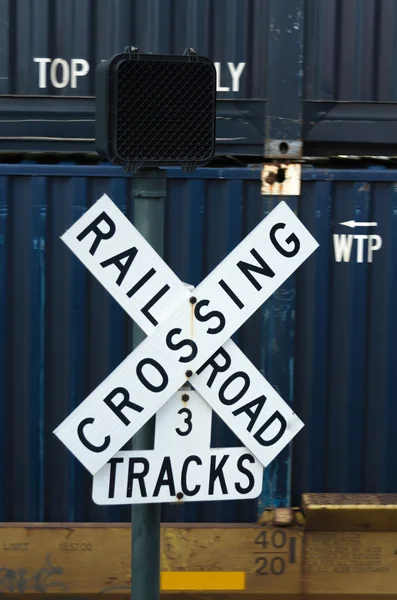 Cartel de cruce de ferrocarril con tren de contenedores de envío en Backgrou — Foto de Stock